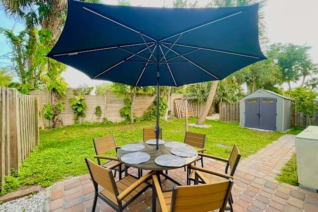 Patio dining table under an umbrella in the fenced backyard at 17316 Fort Myers Beach