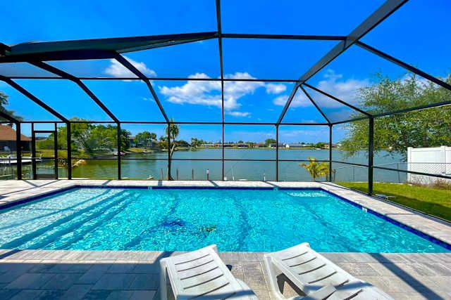 Screened heated pool and sun loungers overlooking the lake at Lakeside Haven, Cape Coral