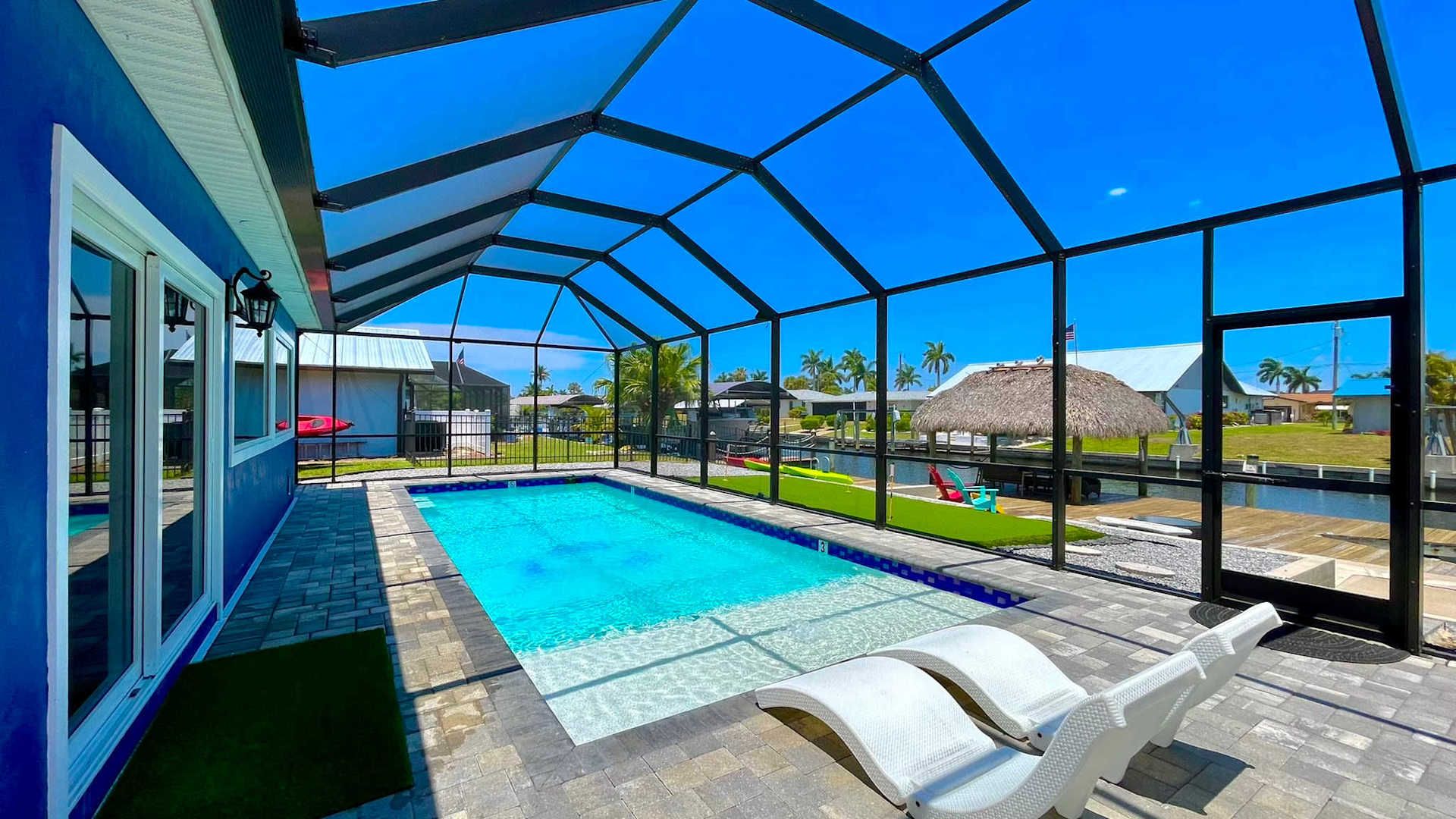 Screened heated pool and lanai looking out to a Gulf-access canal at a Typhu Homes rental in Cape Coral